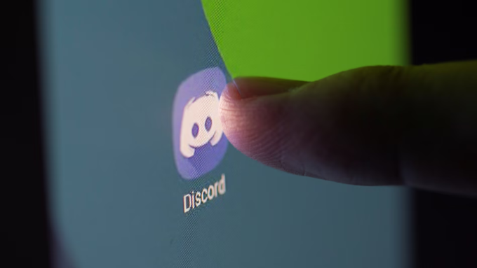 Một phụ nữ chạm vào logo Discord trên màn hình máy tính, chụp vào tháng 3/2021. Ảnh: Reuters