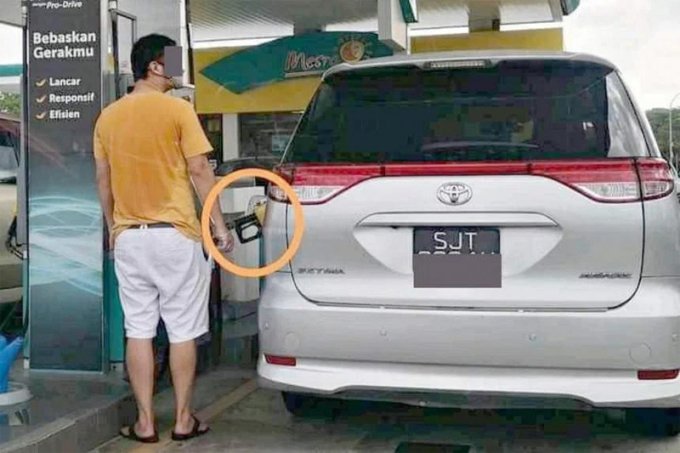 Một chiếc Toyota biển số Singapore đang được nạp xăng RON95 ở một cây xăng tại Malaysia, với phần khoanh tròn vào chỗ tay cầm có màu vàng - màu đặc trưng của vòi bơm xăng RON95. Ảnh: Najib Nazak