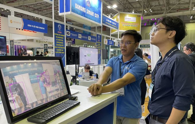 Anh Võ Đức Phú, đại diện Atoma (trái) giới thiệu phần mềm ứng dụng AI quản lý camera tại triển lãm, sáng 13/4. Ảnh: Hà An