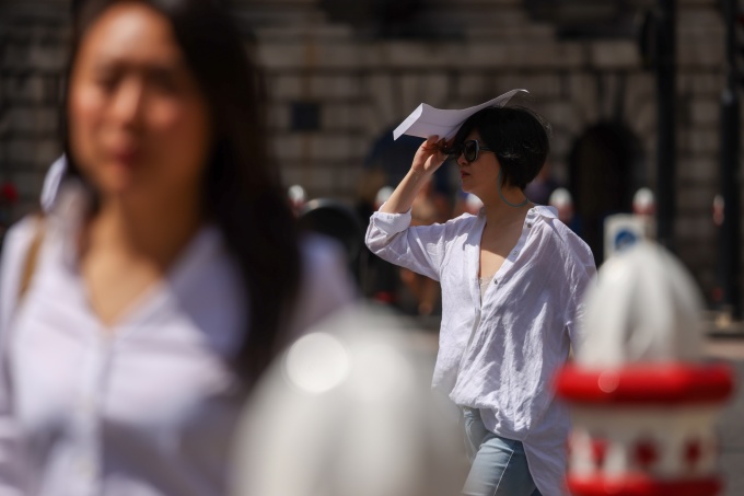 Một người đi bộ sử dụng phong bì để che nắng, ở London, tháng 7/2022. Ảnh: Hollie Adams/Bloomberg